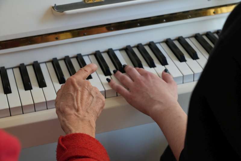 Eine alte und eine junge Hand an einer Klaviertastatur